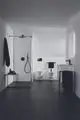 Badezimmeransicht mit bodenebener Dusche, Wandtoiletten und einem Waschtisch. Armatur in Silk Black von Ideal Standard, einfache Gestaltung und funktionale Anordnung.